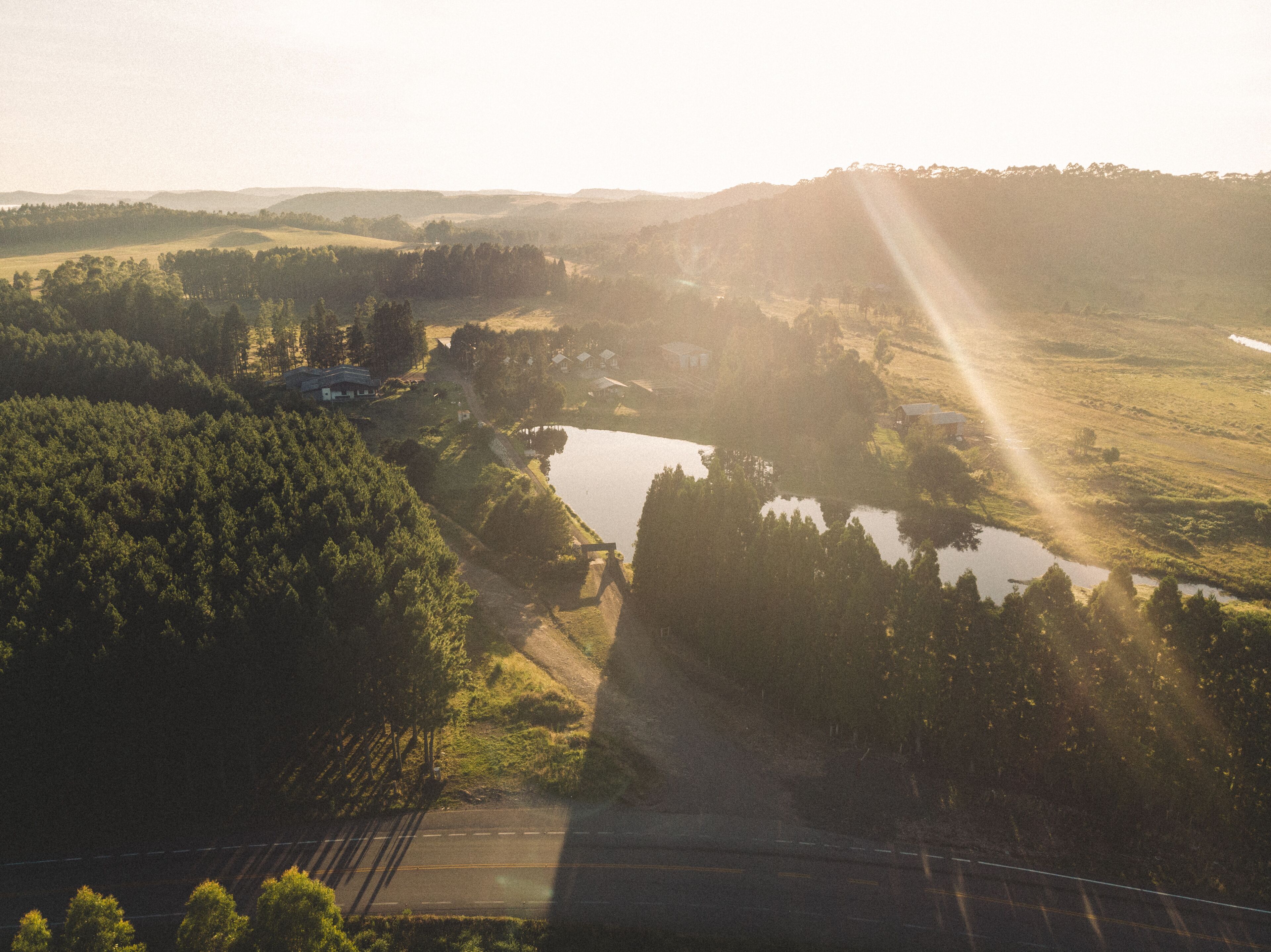 Ett lantligt landskap med en flod, skogsområden och några få byggnader.