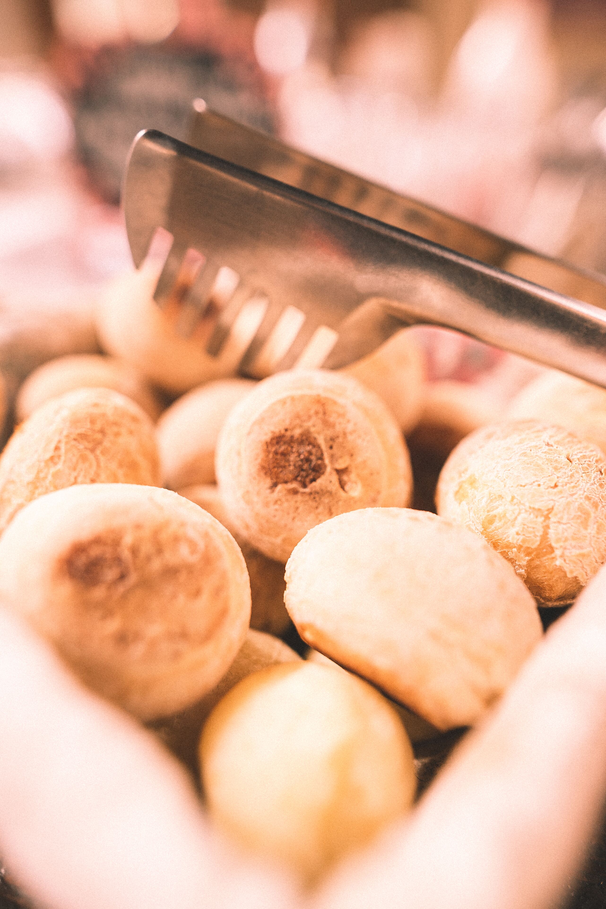 Primer plano de un recipiente lleno de bollos redondos y dorados, probablemente un tipo de pan dulce o pastelería.