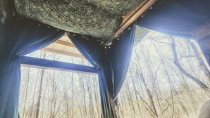 A bedroom with a large window, a bed, and a patterned tapestry. - Lost River Hostel (West Baden Springs)
