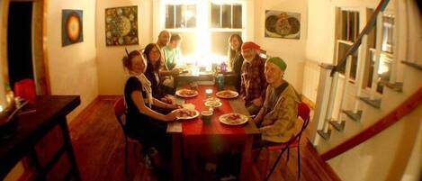 Une salle à manger avec une table et des chaises en bois, entourée de personnes.