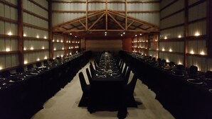 A long banquet hall with tables set for a formal event, high ceilings with wooden beams, and walls lined with windows. - Lost River Hostel (West Baden Springs)