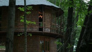 A wooden cabin with a balcony, surrounded by trees. - Lost River Hostel (West Baden Springs)