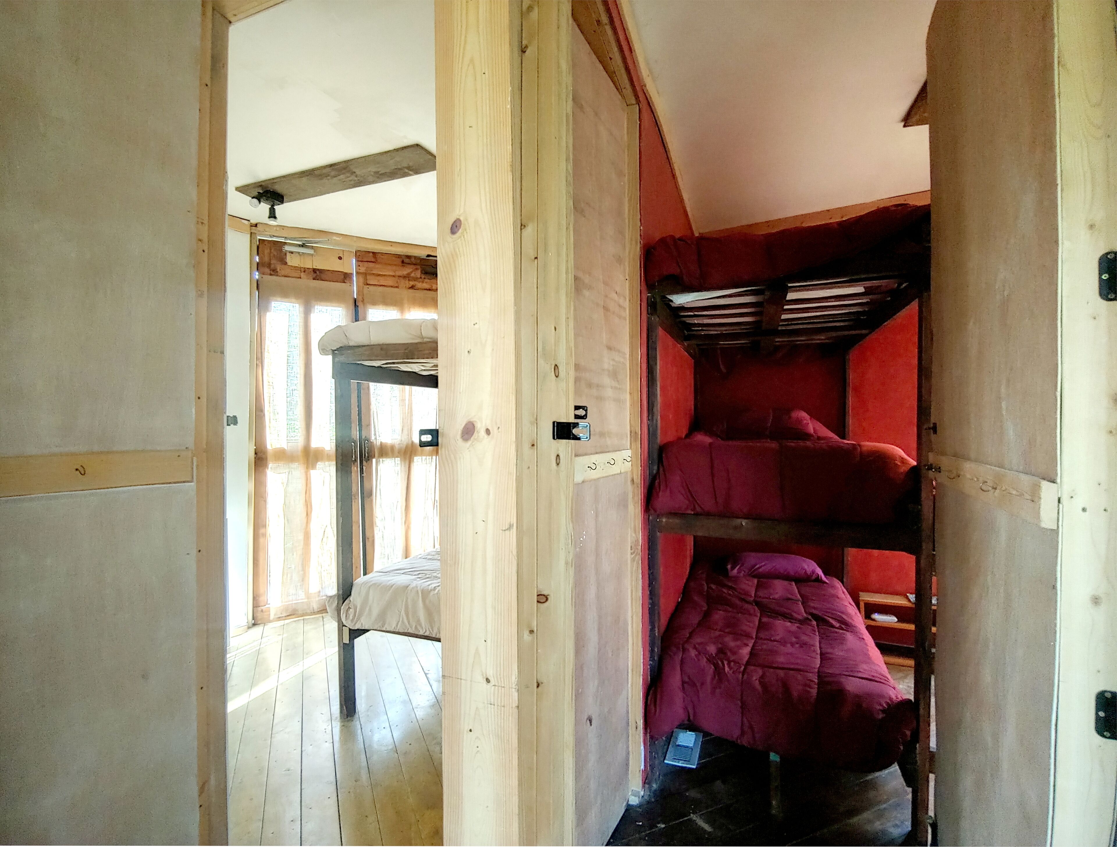 A room with a bunk bed, a window, and a door.