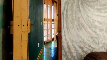 Un pasillo con puerta de madera, pared verde y suelo estampado.