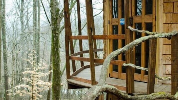 A wooden cabin with a wooden deck and a glass door. - Lost River Hostel (West Baden Springs)