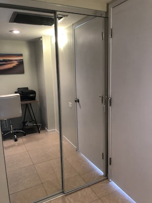 Een moderne kantoorruimte met een glazen scheidingswand, een bureau met stoel en een printer.