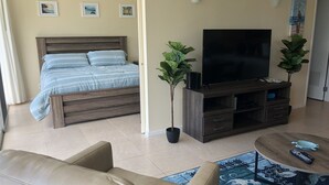 A bedroom with a bed, a TV, and two potted plants. - Beautiful Condo located at Makaha Valley Towers (Waianae)