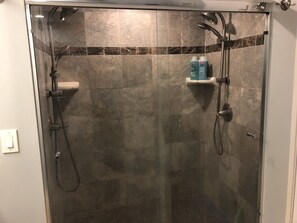 Een bad/douchecombinatie, handdoeken, zeep, toiletpapier
