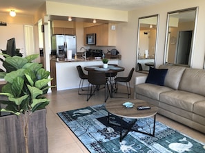 Een moderne woonkamer met een beige bank, een salontafel en een eethoek met een ronde tafel en stoelen.