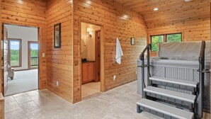 A wooden cabin interior with a bathroom, a hot tub, and a staircase.
