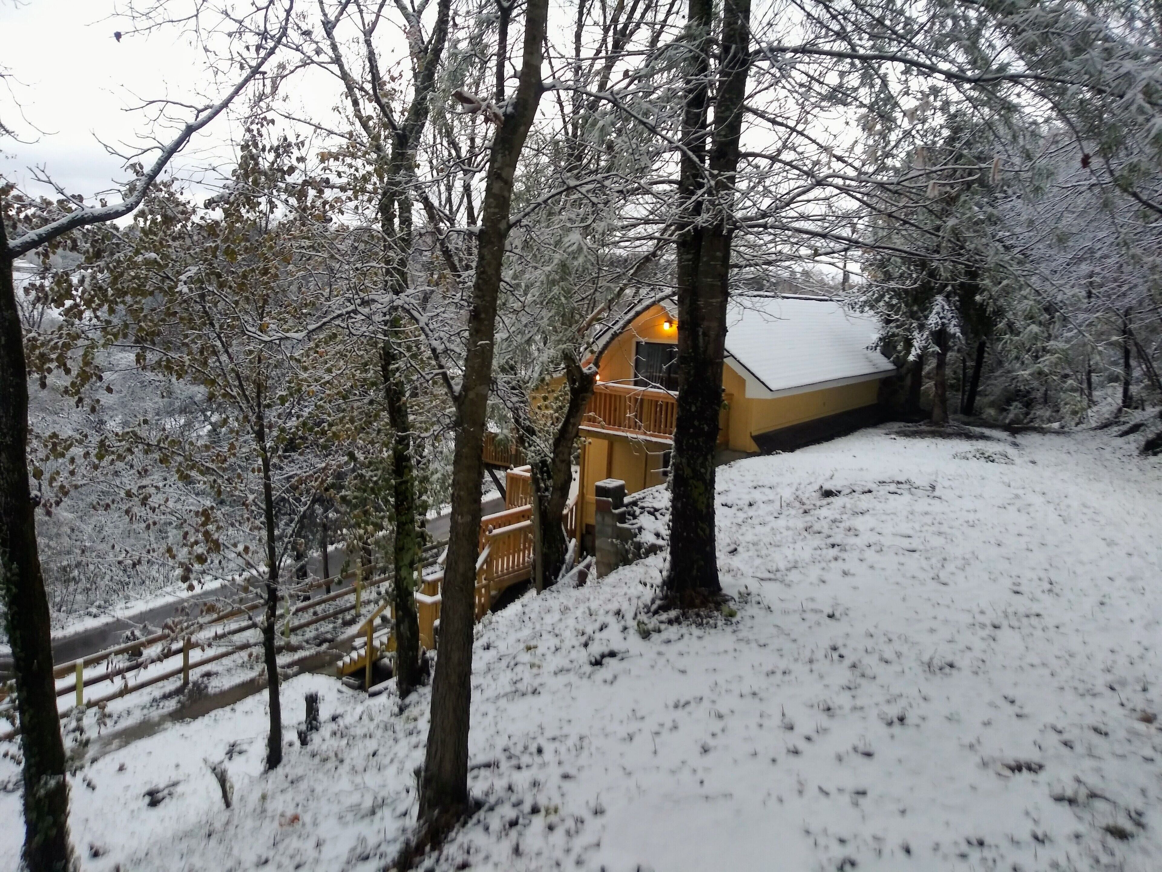 A snow-covered landscape with a wooden cabin and a wooden deck.