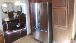 Una cocina con armarios de madera, un refrigerador de acero inoxidable y un comedor con candelabro.