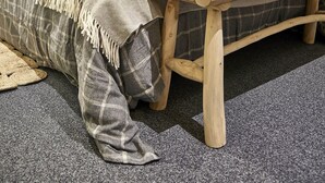 Ein ordentlich eingerichtetes Schlafzimmer mit Bett, Nachttisch und einer kleinen Holzbank.