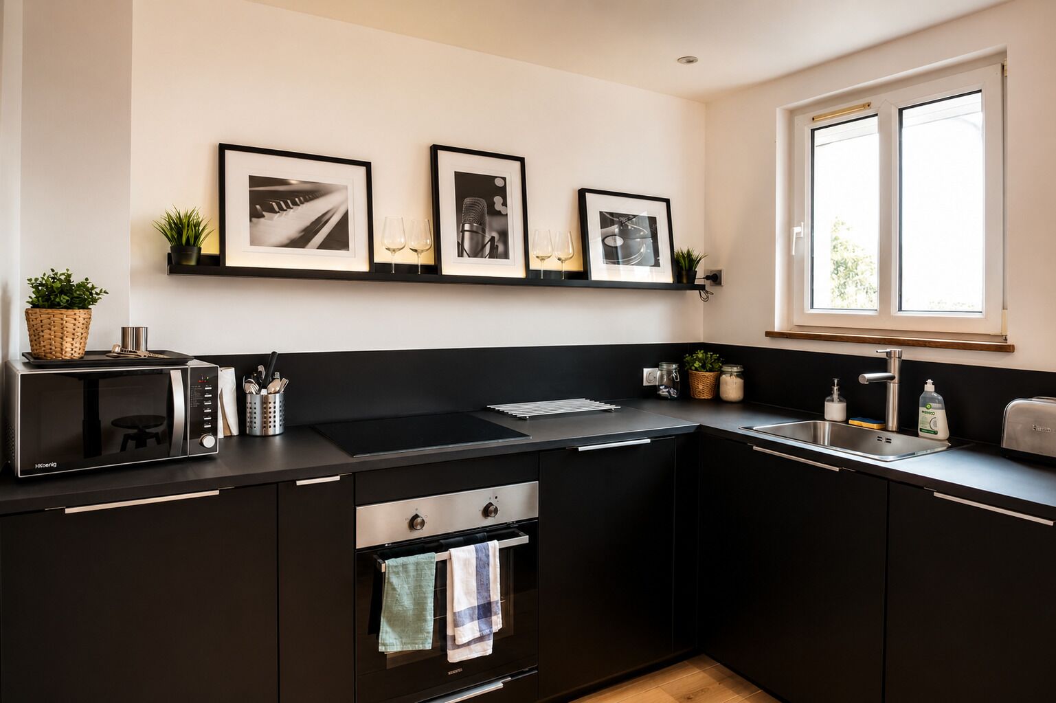 A modern kitchen with a microwave, stove, sink, and framed pictures on the wall.