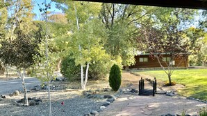 A stone pathway leading to a wooden cabin surrounded by trees and a well-maintained lawn. - Bungalow on a private 70 acre ranch (Austin)