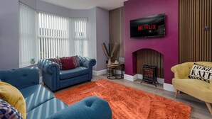 A living room with a blue sofa, a yellow armchair, and a fireplace.
