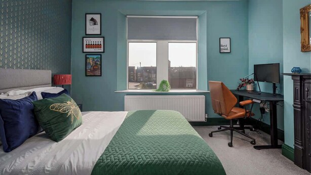 Un dormitorio con cama, escritorio y ventana.