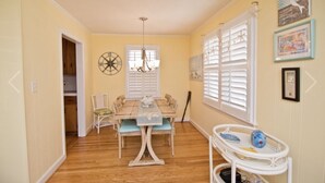 A dining area with a wooden table, chairs, and a small white table with toys. - Beautiful oceanside cottage, steps away from the beach. (Atlantic Beach)