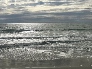 A beach with waves and a cloudy sky.