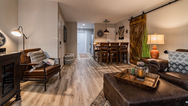 Un salón acogedor con un sofá de cuero marrón, una mesa de centro de madera y una zona de comedor con una mesa y sillas de madera.