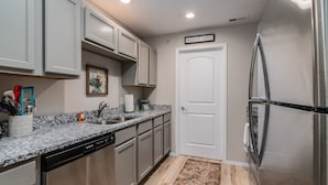 Una cocina con un refrigerador de acero inoxidable, lavavajillas, un fregadero y una puerta con un letrero que dice 'sweet & salty'.