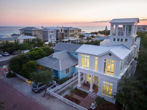 A coastal residential area with multiple houses, including a prominent white house with large windows and a balcony, situated near the beach. - 23 E Ruskin Street by Dune Vacation Rentals (Santa Rosa Beach)