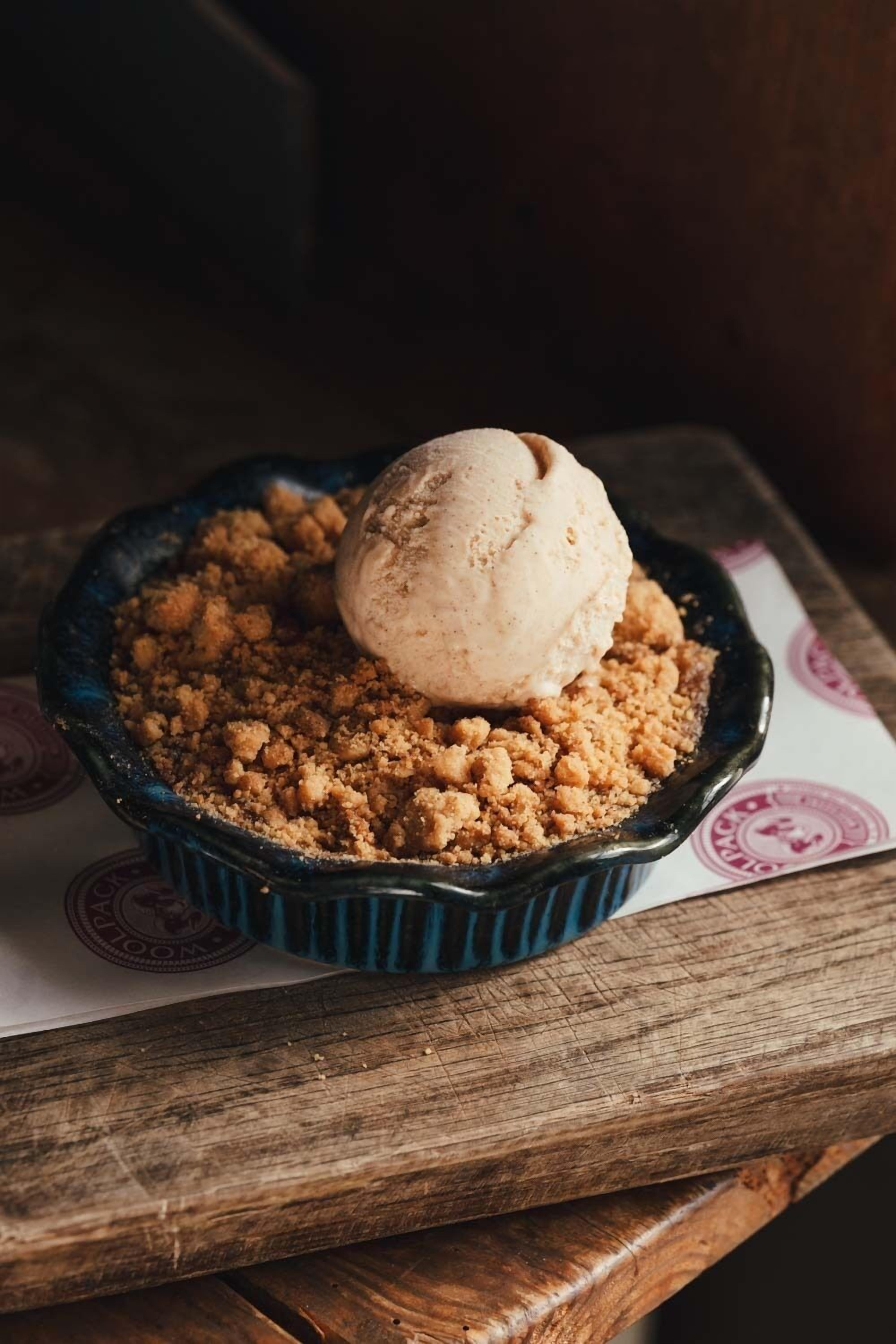 A dessert in a ceramic dish on a wooden table.
