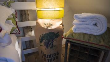 A room with a bed, a lamp, a folded towel, and a bag labeled "QUALITY PORTIONS".