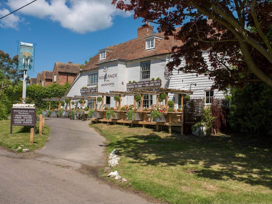 A traditional inn with a signboard, wooden benches, and a pathway leading to the entrance.