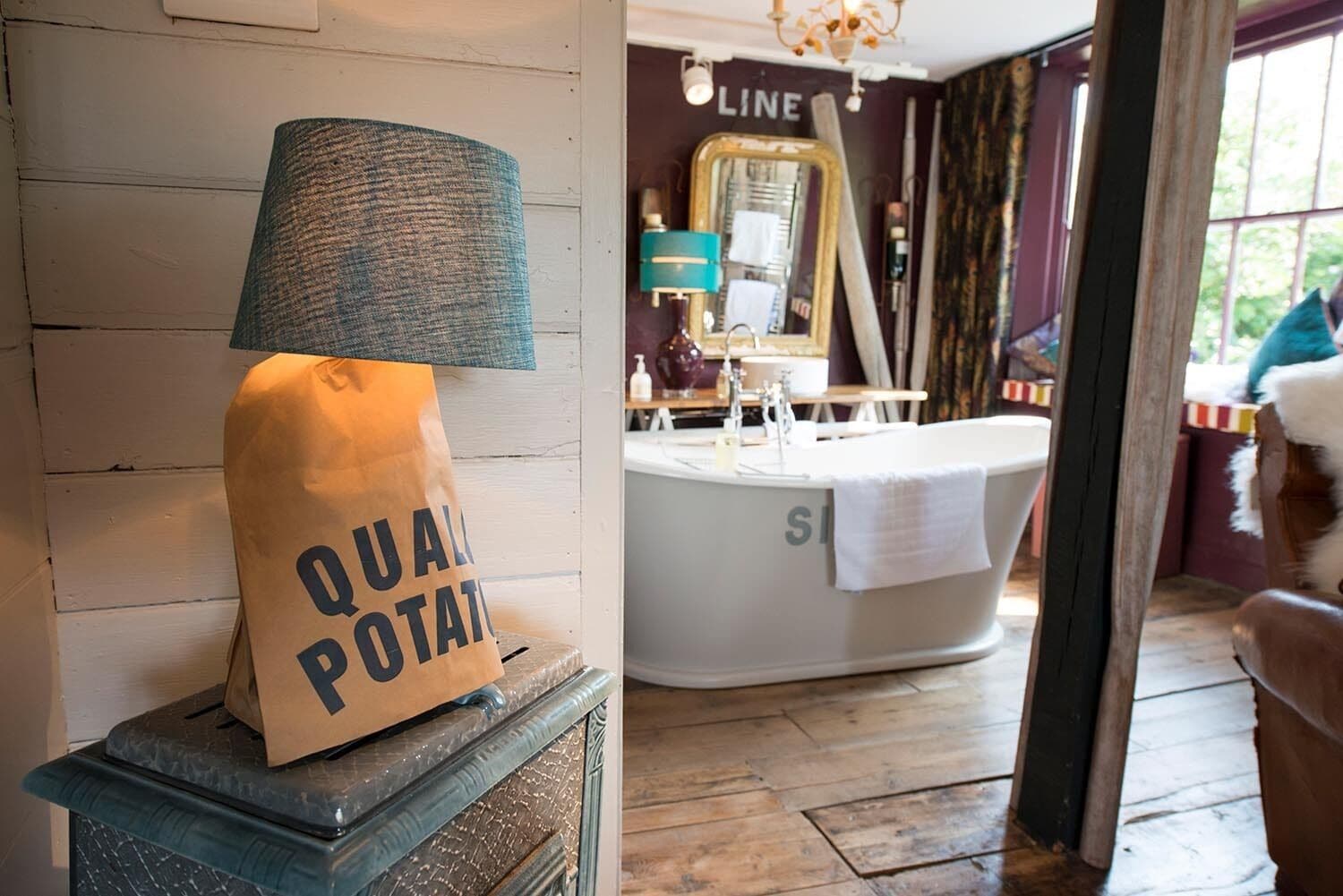 Un baño con una bañera, una toalla y una bolsa etiquetada "QUAL POTAT".
