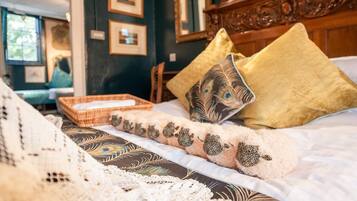 A bed with a patterned blanket, decorative pillows, and a woven basket on the side.