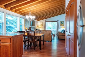 A spacious kitchen with wooden beams, a dining area with a table and chairs, and a living room with a sofa and a television.