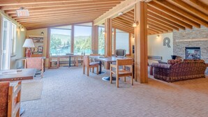 A spacious room with a high ceiling, wooden beams, a fireplace, a large window, and a cozy seating area. - Ranch Condo 3580 -  Elkhorn Resort Amenities (Elkhorn)