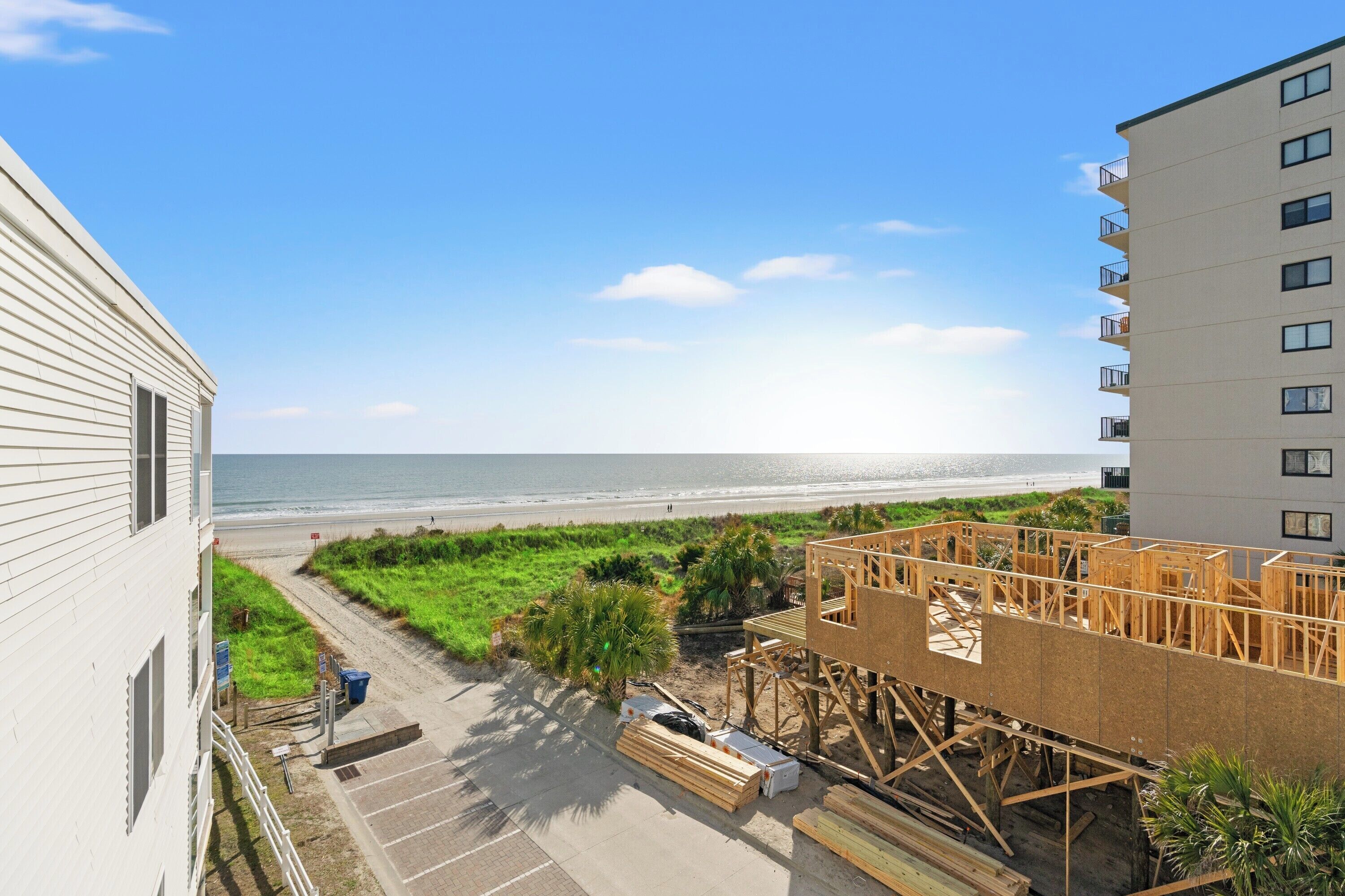 Uitzicht op de kust met een strand, een wit gebouw en een bouwplaats met houten constructies.