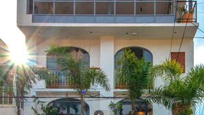 A two-story building with balconies, large windows, and a paved ground.