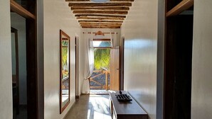 A hallway with a wooden ceiling, a bench, and a door leading outside.