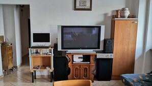 Una sala de estar con televisor, un aparador de madera, una mesita y un sofá.