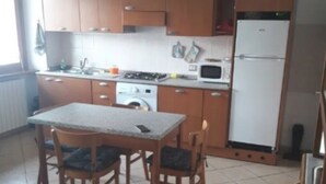 Una cocina compacta con armarios de madera, horno integrado, microondas y lavadora.
