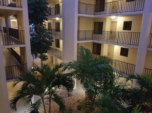 Un vestíbulo de hotel de varios pisos con balcones y palmeras.