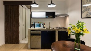 A compact kitchen with modern appliances, a dining area with a vase of flowers, and a wooden door. - Zona Romantica Beautiful Modern Studio (Emiliano Zapata)