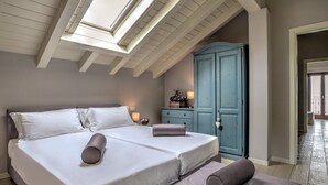 A bedroom with a large bed, a dresser, and a skylight.
