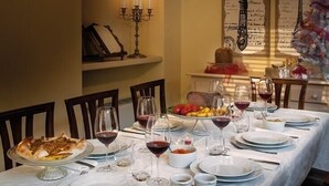 A dining room with a long table set for a meal, featuring a variety of dishes, glasses of wine, and a candelabra.