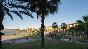 A resort with a beach, palm trees, and a view of the sea. - Paraiso Del Mar Resort E202 2 Bed by Casago (La Paz)