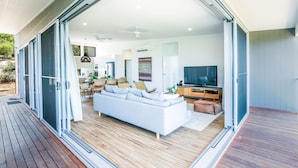 Un espacio habitable moderno y abierto con un sofá blanco, mesa de comedor y televisor.