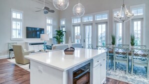 Une cuisine spacieuse dotée d’un îlot central, de grandes fenêtres et d’un éclairage moderne suspendu au plafond.