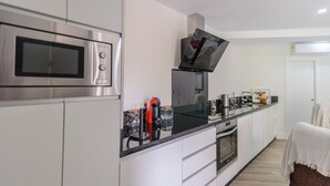 Une cuisine moderne dotée d’appareils électroménagers en acier inoxydable, d’un plan de travail noir et de meubles blancs.