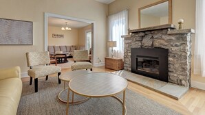 A living room with a stone fireplace, a sofa, two armchairs, a coffee table, and a rug. - 1927 - Murphys Vacation Rentals (Murphys)