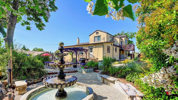 A courtyard with a fountain, a pergola, and a building with a balcony. - 1927 - Murphys Vacation Rentals (Murphys)