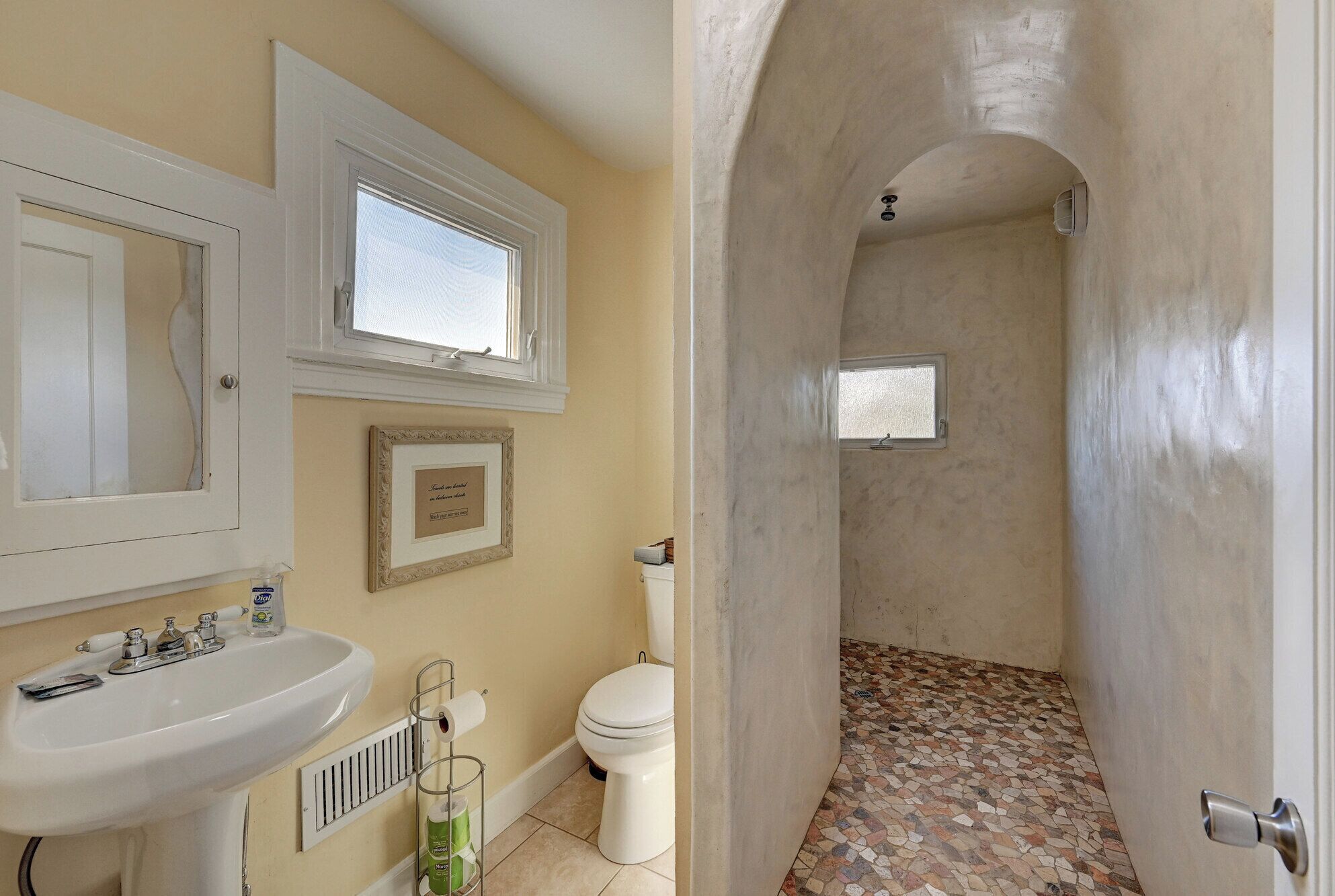 Un baño con lavamanos, inodoro y zona de ducha.