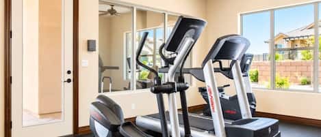 A home gym with two treadmills, a stationary bike, and a mirror.
